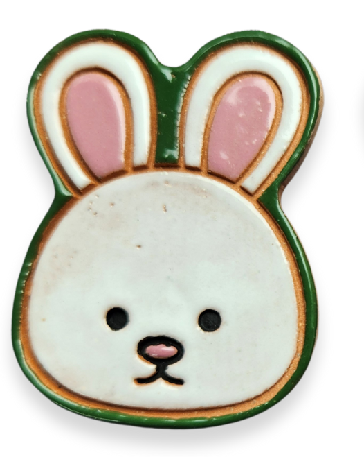 Two inch ceramic tiles shaped like a white bunny head with green outline and pink inner ears, black eyes, and a pink button nose.